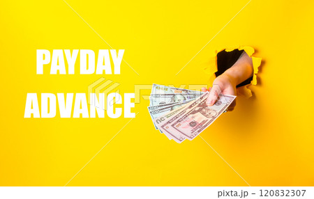 A hand holding a stack of money with the words Payday Advance written below 120832307