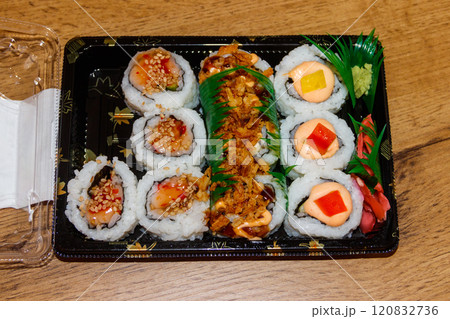 Set of sushi rolls in plastic box on wooden table. Sushi for take away or delivery of sushi in plastic container Set of sushi rolls in plastic box on wooden table. Sushi for take away or delivery of sushi in plastic container 120832736