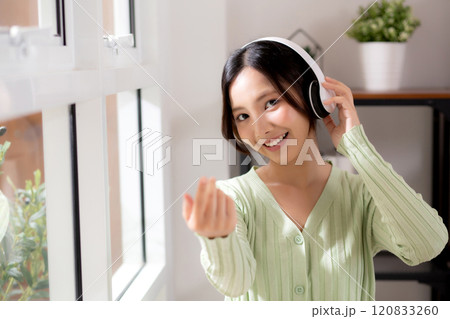 Portrait happy young woman wearing headphones listening music while standing with fun. 120833260