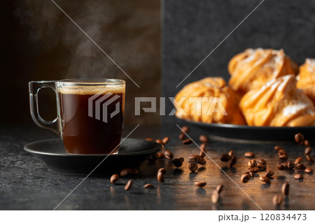 Black coffee in glass cup and coffee beans in motion on a black table. Black coffee in glass cup and coffee beans in motion on a black table. 120834473