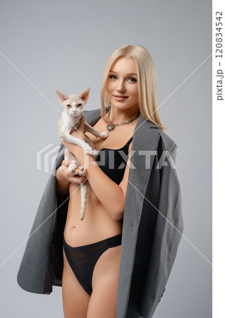 Young woman poses confidently with a cat in a stylish studio setting Young woman poses confidently with a cat in a stylish studio setting 120834542