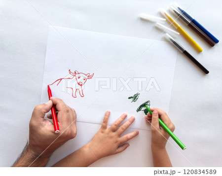 Father and child create animal drawing together using vibrant markers 120834589