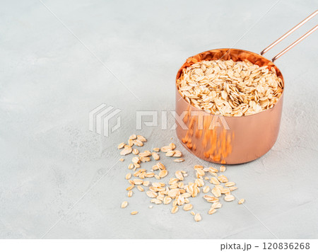 Rolled oats in measuring cup on wooden board Rolled oats in measuring cup on wooden board 120836268
