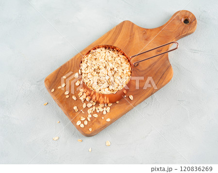 Rolled oats in measuring cup on wooden board Rolled oats in measuring cup on wooden board 120836269