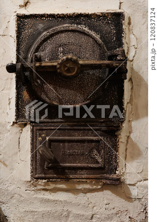 Antique cast iron furnace door with intricate details and a weathered surface 120837124