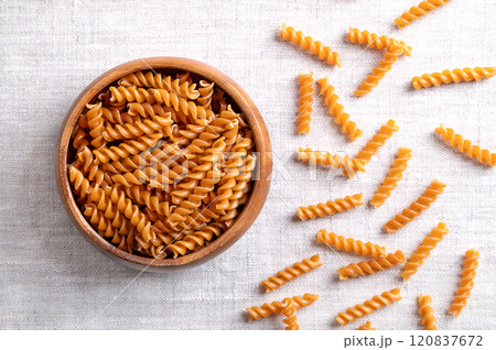 Chickpea spiral pasta, gluten free noodles in a wooden bowl on linen fabric. Small fusilli, a pasta variety with helical or corkscrew shape, made of chickpea flour, an alternative to wheat flour. Chickpea spiral pasta, gluten free noodles in a wooden bowl on linen fabric. Small fusilli, a pasta variety with helical or corkscrew shape, made of chickpea flour, an alternative to wheat flour. 120837672