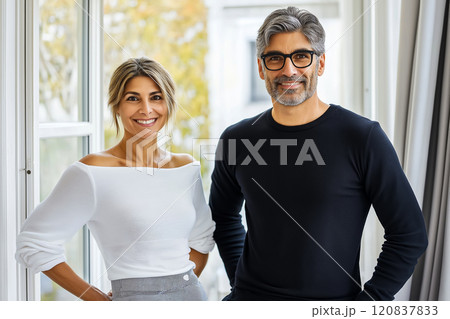 Confident business duo, smiling and standing in a bright modern office with natural light Confident business duo, smiling and standing in a bright modern office with natural light 120837833