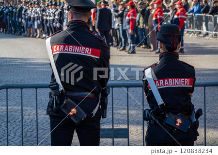Two carabinieri officers monitoring a public event behind a barricade Two carabinieri officers monitoring a public event behind a barricade 120838234