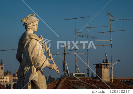 Stone statue overlooking rooftops and antennas in Verona's skyline 120838237