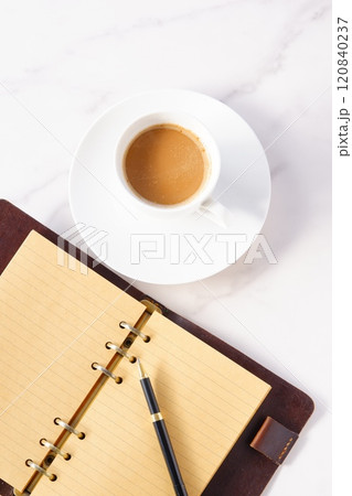 ミルクをたっぷり入れたコーヒー、カフェ・ラッテを飲みながら、システム手帳でデスクワーク中のイメージ 120840237