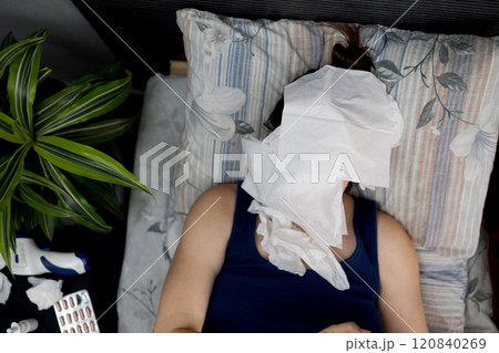 A Sick Individual Lying in Bed Resting while Holding a Tissue for Comfort and Relief 120840269