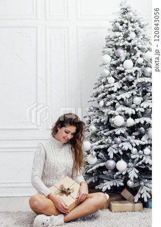 Beautiful woman at a Christmas tree decorated with garlands and gifts for the new year 120843056