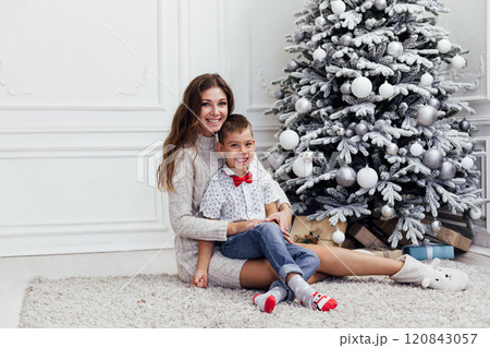 Mother and son at Christmas tree decorated with garlands and gifts for the new year Mother and son at Christmas tree decorated with garlands and gifts for the new year 120843057