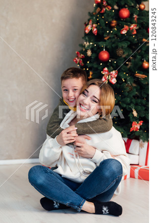 Mom and son decorating Christmas tree with gifts and garlands Mom and son decorating Christmas tree with gifts and garlands 120843245