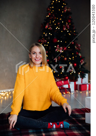 blonde woman smiling at Christmas tree with gifts for new year 120843380