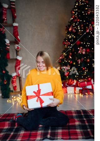 Beautiful woman smiling and opening gifts at Christmas tree for new year Beautiful woman smiling and opening gifts at Christmas tree for new year 120843382