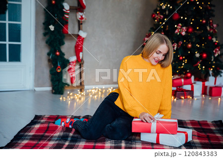 Beautiful woman smiling and opening gifts at Christmas tree for new year Beautiful woman smiling and opening gifts at Christmas tree for new year 120843383