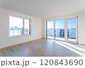 Empty living room with laminate floor and french windows offering city view 120843690