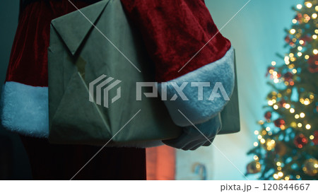 Santa Claus walks with a Christmas present under his arm 120844667