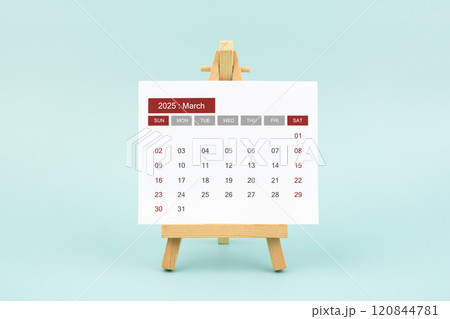 Calendar page for March 2025 with wood easel on a blue background. 120844781