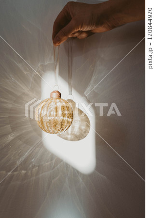 Woman hand holding a vintage gold-colored Christmas ornament on a white background Woman hand holding a vintage gold-colored Christmas ornament on a white background 120844920