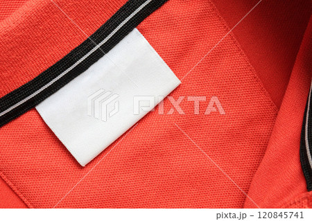 Blank white laundry care clothes label on orange shirt fabric texture background 120845741