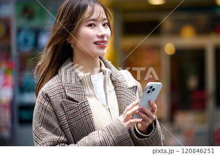 スマホを持つ冬服の若い女性 120846251