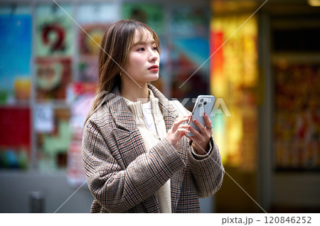 スマホを持つ冬服の若い女性 120846252
