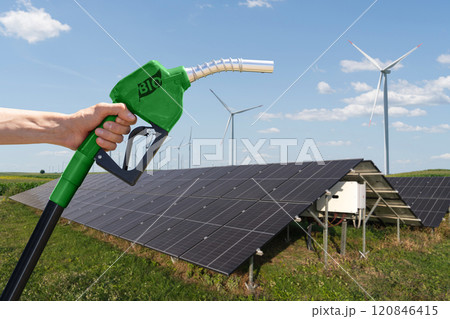 Hand with biofuel refueling nozzle on a background of solar panels Hand with biofuel refueling nozzle on a background of solar panels 120846415