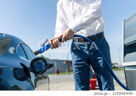 Man holds a hydrogen fueling nozzle on a hydrogen filling station. Refueling car with hydrogen fuel. 120846440