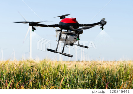 Drone sprayer flies over the agricultural field. Wind turbines on a horizon.Drone sprayer flies over the agricultural field. Wind turbines on a horizon Drone sprayer flies over the agricultural field. Wind turbines on a horizon.Drone sprayer flies over the agricultural field. Wind turbines on a horizon 120846441