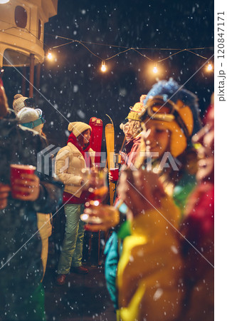 Festive vibes fill air as friends dressed in winter clothes toast together under snowfall, enjoying warm drinks and cheerful company. Festive vibes fill air as friends dressed in winter clothes toast together under snowfall, enjoying warm drinks and cheerful company. 120847171