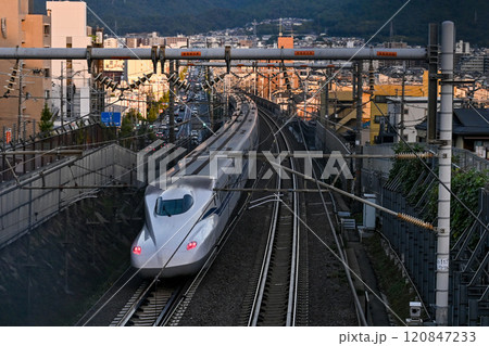 【京都】夕日があたる街中を一気に走り抜ける新幹線 120847233