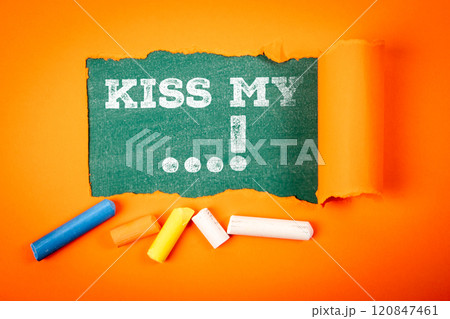 Kiss My. Discontent and rudeness. Text under torn orange paper on a green chalkboard 120847461