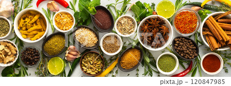 Assorted cooking spices and herbs arranged on a gray surface, featuring natural tones that add depth and aroma to any meal, banner 120847985