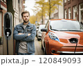 Serious Man with Arms Crossed at EV Charge Point 120849093