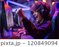 Young gamer enthusiastically celebrating a victory while playing computer games in a gaming club 120849094