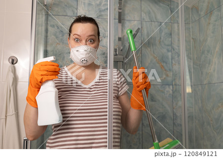 A person diligently cleaning a shower space while wearing gloves and a protective mask A person diligently cleaning a shower space while wearing gloves and a protective mask 120849121