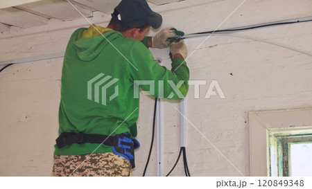 An electrician conducts wiring in a wooden house. 120849348