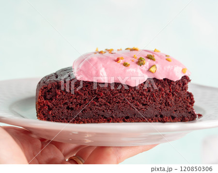 Piece of beetroot chocolate cake with pink cream cheese icing 120850306
