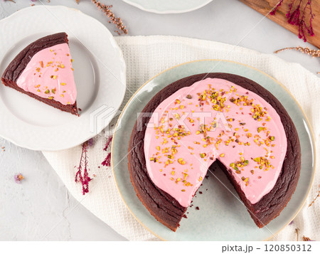 Piece of beetroot chocolate cake with pink cream cheese icing 120850312