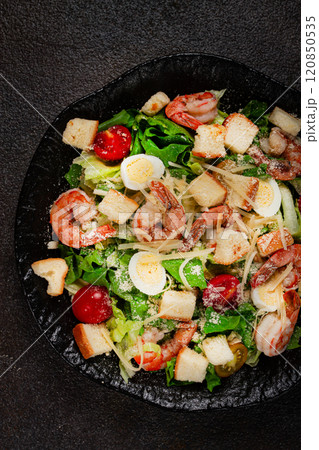 caesar salad with tiger prawns, shrimp salad, lettuce leaves, quail eggs, cherry tomatoes, parmesan cheese, on a black plate, caesar salad with tiger prawns, shrimp salad, lettuce leaves, quail eggs, cherry tomatoes, parmesan cheese, on a black plate, 120850535