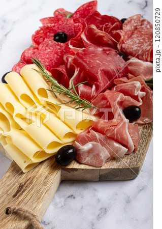 Assorted meat, appetizer, prosciutto, salami and ham, with maasdam cheese and olives, on a wooden board, breakfast, top view, close-up, no people 120850729