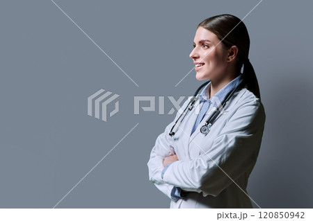Profile view of young positive female doctor with stethoscope on gray background 120850942