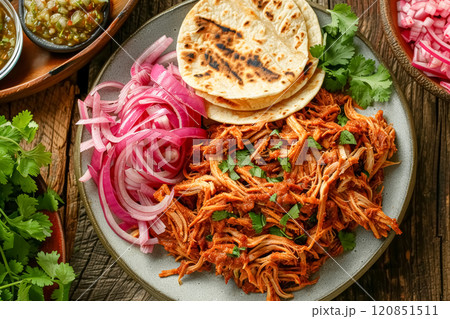Top view of plate on wooden table with dish cochinita pibil slow-roasted marinated pork, served with tortillas and pickled red onions, traditional mexican cuisine 120851511