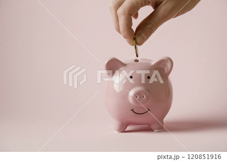 Hand puts a coin in a piggy bank. 120851916