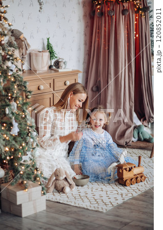 Smiling girl with mom near christmas tree at home 120852011