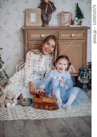 Smiling girl with mom near christmas tree at home 120852073