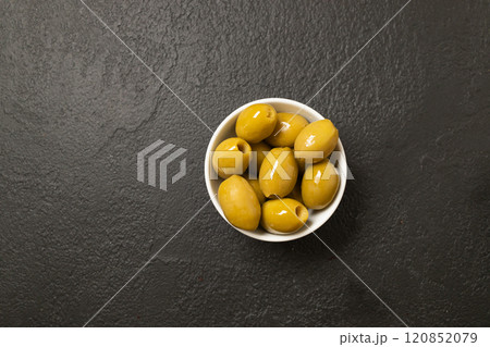 Whole green olives in white bowl on black background. Top view, close-up Whole green olives in white bowl on black background. Top view, close-up 120852079