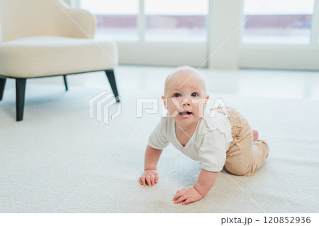 Happy baby. Cute little newborn girl with smiling face crawling on floor in bedroom. Infant baby resting playing in living room indoor at home. Motherhood happy child childcare concept 120852936